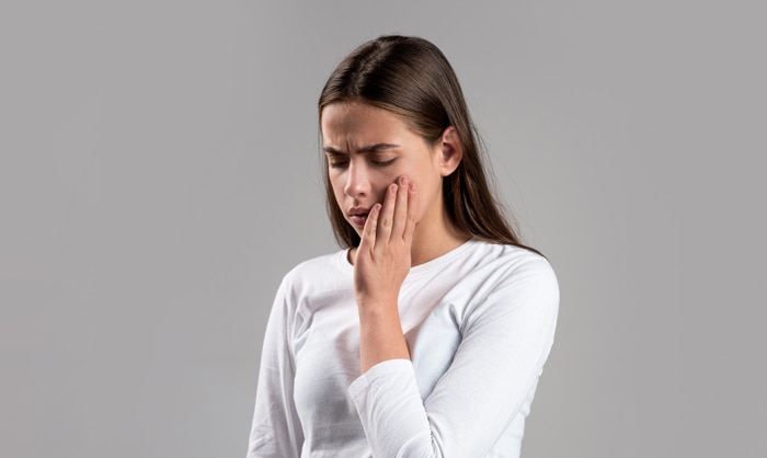 Kvinne holder seg for kinnet