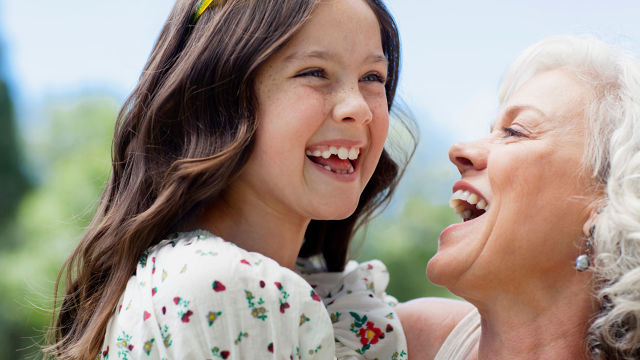 A grandmother and granddaughter smiling together, enjoying a joyful moment.